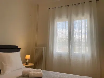 a bedroom with a window with a white curtain at Koukaki lovely stay in Athens