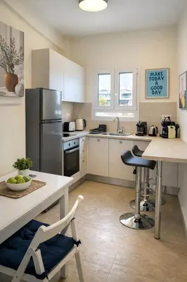 a kitchen with a refrigerator and a table with chairs at Koukaki lovely stay in Athens