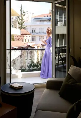 a woman in a purple dress standing on a balcony at AthenSun Luxury Suites in Athens