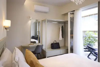 a bedroom with a bed and a chair and a mirror at AthenSun Luxury Suites in Athens