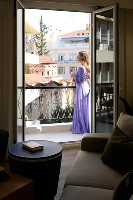 a woman in a purple dress standing on a balcony at AthenSun Luxury Suites in Athens