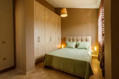 a bedroom with a bed with green sheets and a cabinet at Villa Vegera in Anavissos