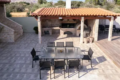 a table and chairs on a patio with a fireplace at Villa Vegera in Anavissos