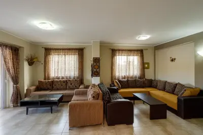 a living room with couches and tables and windows at Villa Vegera in Anavissos