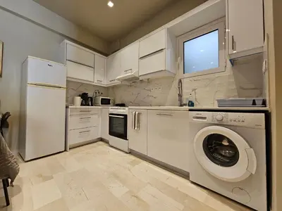 a kitchen with white cabinets and a washer and dryer at J&G Luxury Apartment - Athens Town in Athens