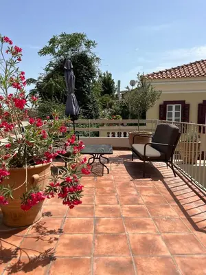 a patio with two chairs and flowers and an umbrella at Acropolis View-Themelio Suite - Acropolis Area in Athens