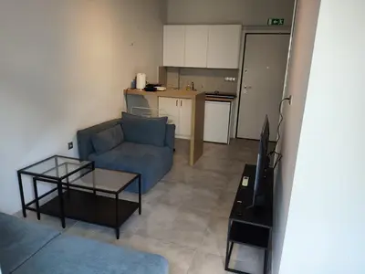a living room with a blue couch and a kitchen at Modern apt in downtown by MK in Athens