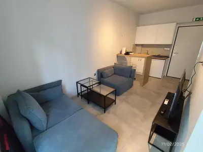 a living room with a blue couch and a kitchen at Modern apt in downtown by MK in Athens