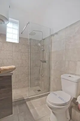 a bathroom with a toilet and a glass shower at Just Home Cozy Fully Renovated Apt in Athens