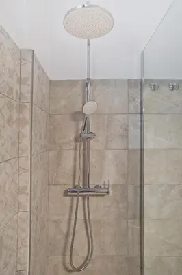 a shower with a shower head and a glass door at Just Home Cozy Fully Renovated Apt in Athens