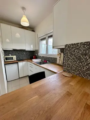 a kitchen with white cabinets and a wooden table at Acropolis Loft 26 in Athens