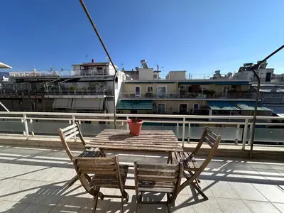 a wooden table and chairs on a deck with a ship at Acropolis Loft 26 in Athens