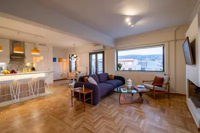 a living room with a blue couch and a kitchen at Athens Panorama Penthouse by Acropolis in Athens