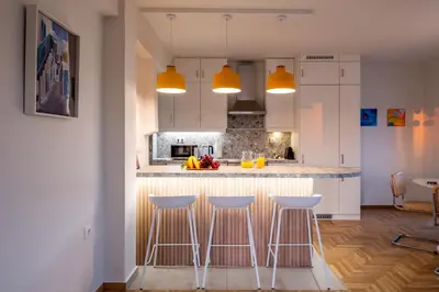 a kitchen with white cabinets and bar stools at Athens Panorama Penthouse by Acropolis in Athens