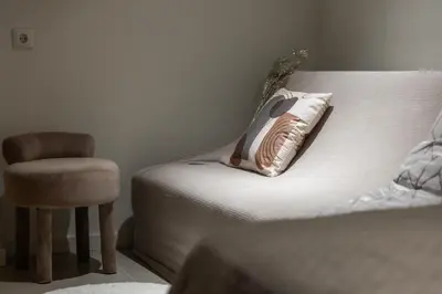 a bed with a pillow and a chair in a room at Vouliagmeni Square Resort in Athens