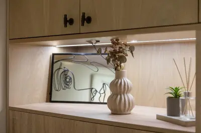 a vase with flowers sitting on a shelf with a painting at Vouliagmeni Square Resort in Athens