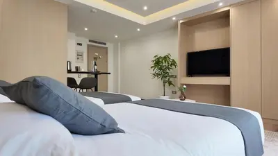 a hotel room with three beds and a flat screen tv at CC LUX Suites in Piraeus Port in Piraeus