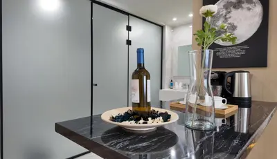 a bottle of wine sitting on a glass table with a vase at CC LUX Suites in Piraeus Port in Piraeus