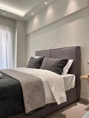 a bedroom with a large bed with a gray headboard at J seaside cozy APT in Athens