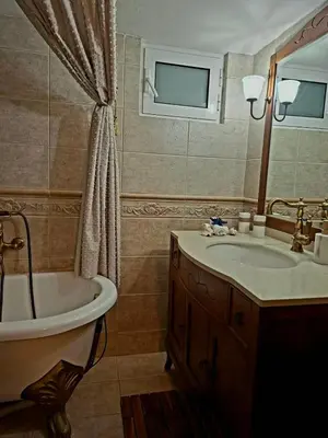 a bathroom with a tub and a sink and a mirror at STONE of KAMARIZA in Áyios Konstandínos