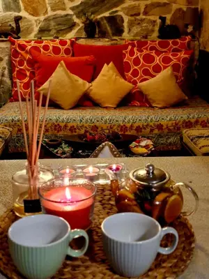 a table with tea cups and candles and a couch at STONE of KAMARIZA in Áyios Konstandínos
