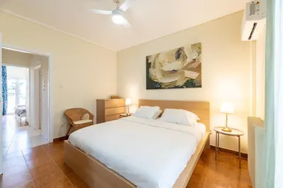 a bedroom with a white bed and a painting on the wall at A2 3-Bedrms Ap 112sm 850m Metro Evangelismos 150m EKPA Univ Campus 100m Bus Stop to Acropolis in Athens