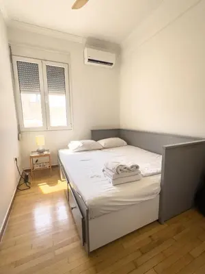 a white bedroom with a bed and two windows at Bright Apartment Syntagma Square in Athens