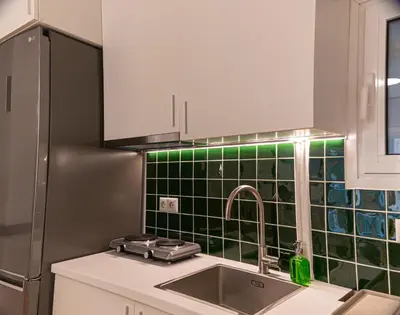 a kitchen with a sink and a green tiled wall at Elegant Minimal Apartment in Athens