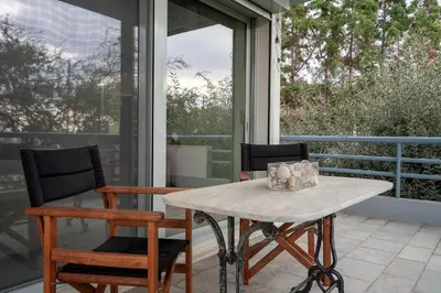 a table and chairs on a patio with a window at Athenian Riviera Seafront Residence in Saronida