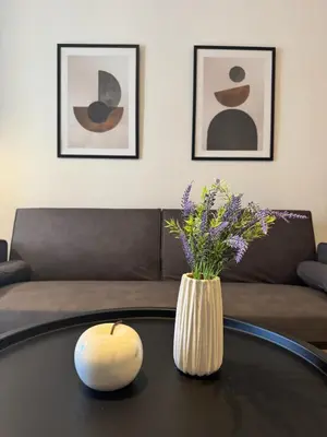 a living room with a table with a vase of flowers at To Kyma Apartment Athens South in Athens
