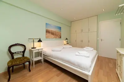 a bedroom with a white bed and a chair at Spacious Apartment Downtown Glyfada in Athens