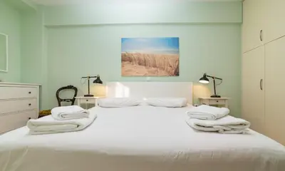 a bedroom with a white bed with towels on it at Spacious Apartment Downtown Glyfada in Athens