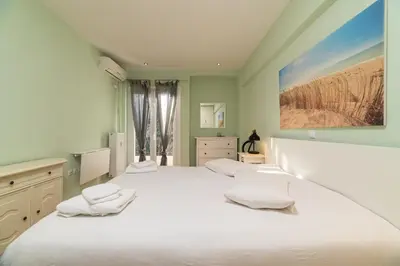 a white bedroom with two beds and a painting on the wall at Spacious Apartment Downtown Glyfada in Athens