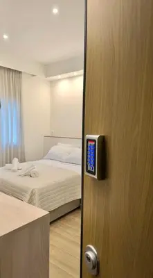 a bedroom with a bed and a door with a remote control at Urban Pad Athens in Athens