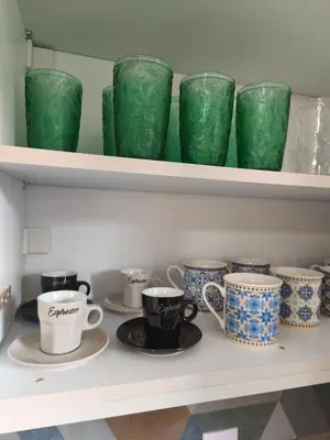 a shelf filled with green and white cups and saucers at Acropolis Sweet House 6 in Athens