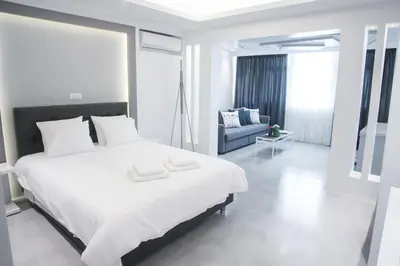 a white bedroom with a large bed and a couch at Millennial Apartments Athens in Athens