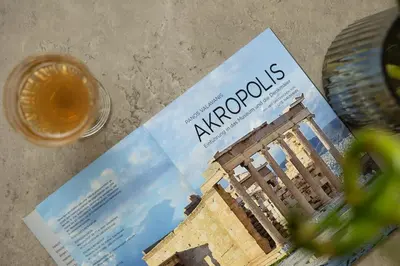 a magazine sitting on top of a table with a drink at Sunny Athenian Apartment in Athens
