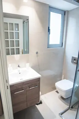 a bathroom with a sink and a toilet and a window at Millennial Apartments Voulis in Athens