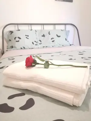 a bed with a white blanket and a rose on it at Andy's sweet house in Athens