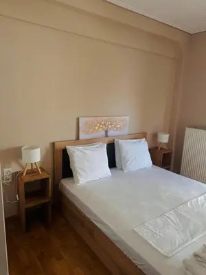 a bedroom with a bed with white sheets and two lamps at Βένερε in Athens