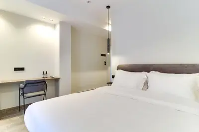 a bedroom with a large white bed and a chair at ABOV Acropolis in Athens