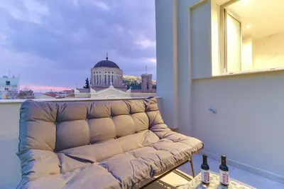 a couch in a room with a view of a building at ABOV Acropolis in Athens