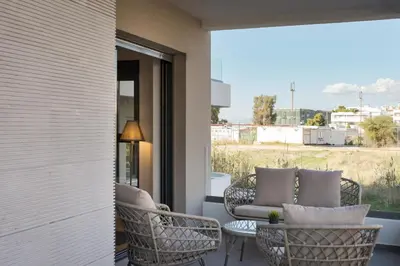 a patio with wicker chairs and a table on a balcony at Glyfada Experience Residence in Athens