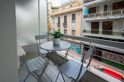 a small table and chairs on a balcony with a window at Mia Homes - National Museum in Athens
