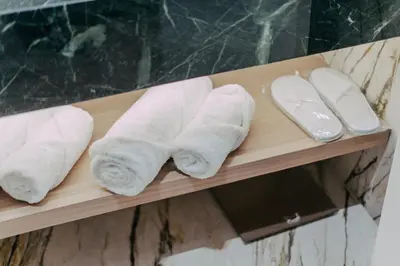 three rolled towels on a shelf in a bathroom at Eternity Athens in Athens