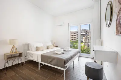 a white bedroom with a bed and a window at GK Agorakritou in Athens