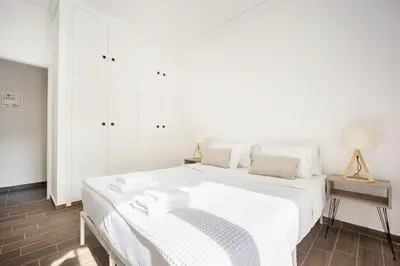 a white bedroom with a white bed and a table at GK Agorakritou in Athens