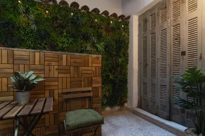 a patio with a green wall with a table and a bench at Prime Location Kolonaki Burrow in Athens