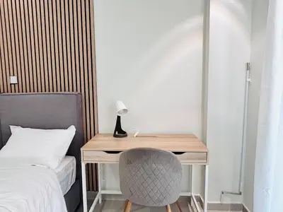 a desk with a lamp and a chair next to a bed at T seaside cozy APT in Athens