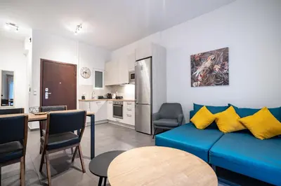 a living room with a blue couch and a kitchen at Evaggelismos Apt Metro Station 1 bdrm 2pers by MPS in Athens